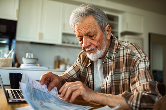 Senior man reviewing bills at home kitchen table