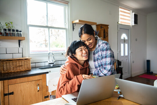 Happy couple hugging while working from home in kitchen