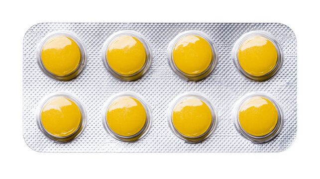 Isolated yellow round pills in a metallic silver blister pack for medication and healthcare.