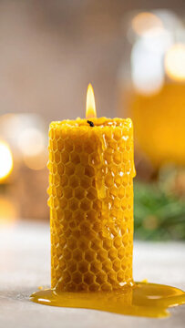 Honeycomb candle with glowing flame and melted wax, warmly lit against softly blurred background, creating calm handmade atmosphere