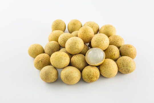 A cluster of whole fresh longan fruits with one peeled to show its translucent white flesh, set against a plain white background.
