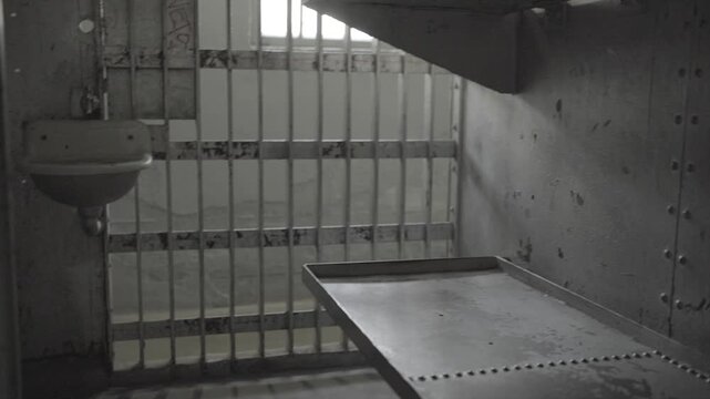 A dark and gloomy, industrial-style panning shot inside an old steel prison cell. 