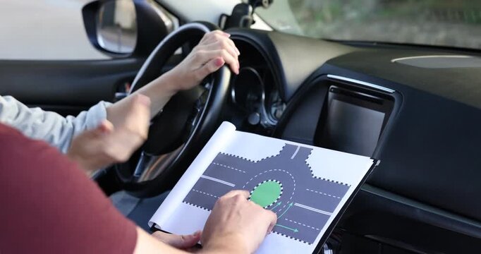 Driving school. Instructor showing student scheme of roundabout in car, closeup