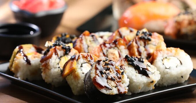 Tasty sushi rolls and soy sauce on wooden table, closeup. Camera zooming in