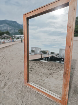 Wooden frame mirror reflecting beach and sky