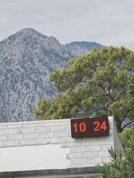 Digital clock displaying time near mountain backdrop