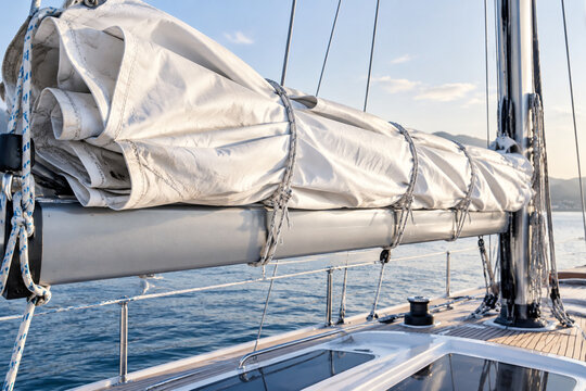 A furled white sail tightly bound to a yacht boom, crisp folds.