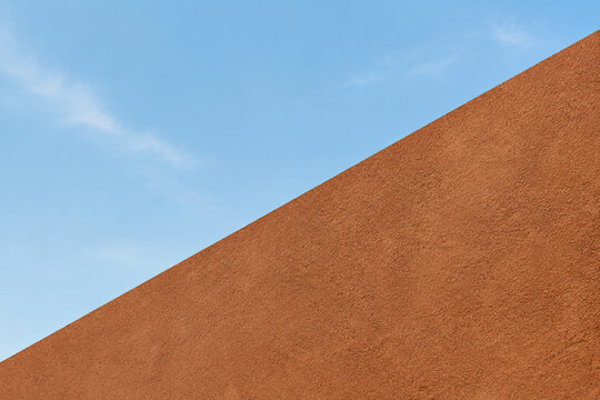 A bold diagonal line divides a soft sky from a textured earth tone surface.