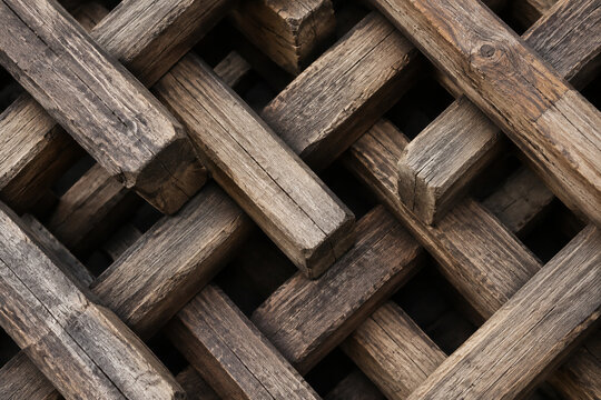 Geometric pattern of interlocking rough wooden beams forming a tight structure, top-down view.
