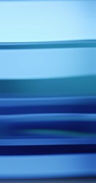 Radiant blue lights illuminate the brilliance of moving reflective glass creating a gradient of soft blues for a calm, relaxing aura. Smooth dreamy blue lighting abstract background or wallpaper Loop