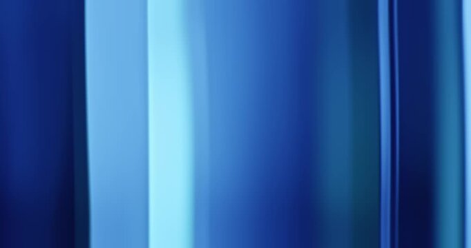Radiant blue lights illuminate the brilliance of moving reflective glass creating a gradient of soft blues for a calm, relaxing aura. Smooth dreamy blue lighting abstract background or wallpaper Loop
