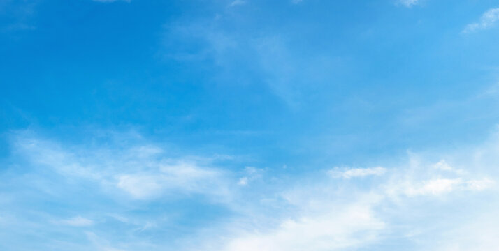 Clear blue sky with soft, wispy clouds drifting gently