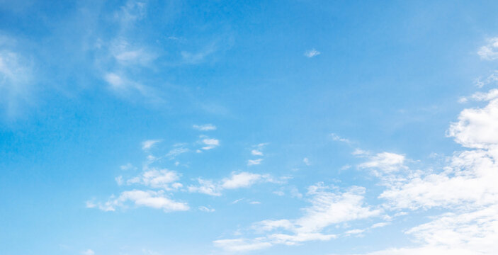 Soft clouds drift across clear blue sky