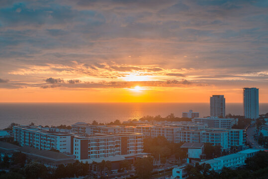 Aerial view of coastal city skyline and ocean horizon during golden sunset. Real estate and travel concept. Human-created, not AI.