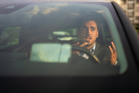 Man using smartphone voice assistant while driving