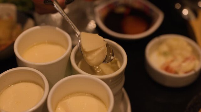 Woman Scooping Savory Chawanmushi Egg Custard with Spoon in Restaurant