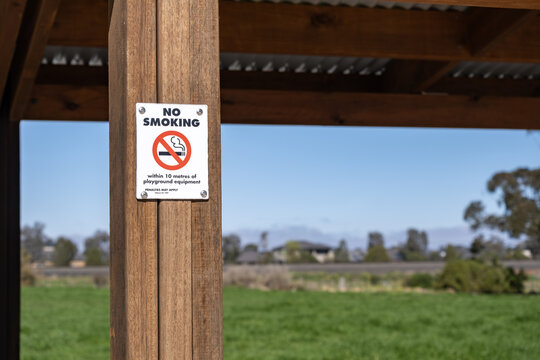Official "No Smoking within 10 metres of playground equipment" sign mounted on a shelter post in a public park in Melbourne, Victoria, Australia. Public health regulation and rule