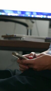 自宅で勉強に集中せずスマホを触る学生、学習中にスマートフォンに触れる学生、ドーパミン中毒注意　手元のクローズアップ顔無しのイメージの縦動画