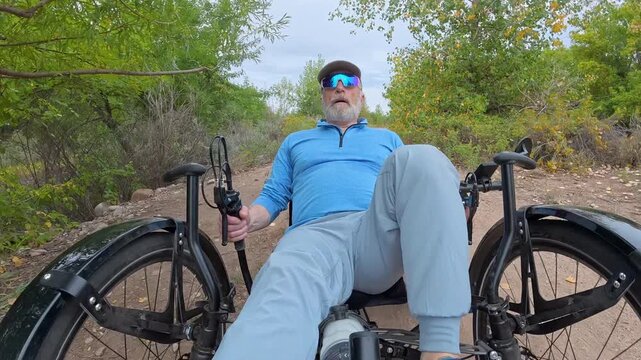 Senior cyclist is riding a full suspension recumbent tricycle on a rough gravel trail in northern Colorado - late summer scenery with rabbitbrush in North Shields Ponds Natural Area