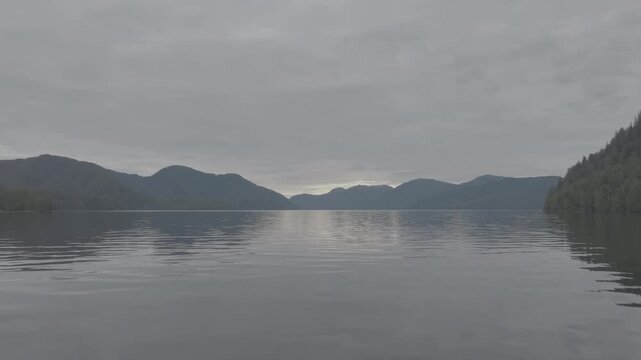Aerial view of mirror calm water and layered mountain ridges in a coastal fjord at dawn &mdash; minimal horizon with copy space