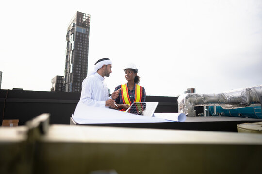 Rooftop solar feasibility study with a property client as a small photovoltaic panel is laid out on the ledge, with a wall of residential towers rising behind them.