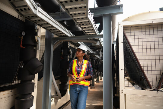 Technician and colleague testing cooling equipment as the reading is compared against the expected value, with daylight flooding the end of the equipment gallery.