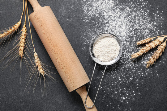 Baking and culinary arts, wooden rolling pin with wheat stalks and flour sieve on dark stone background for homemade bread and pastry preparation