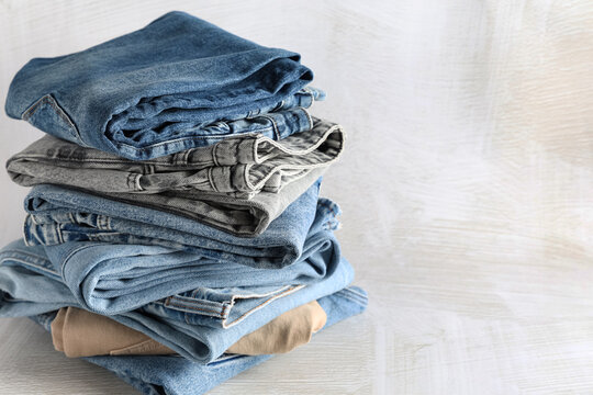 Sustainable fashion and clothing consumption, stack of folded denim jeans and trousers for wardrobe organization and laundry concept on wooden background