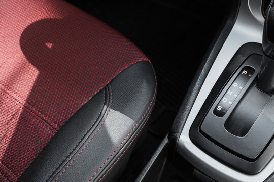 Automotive design and car interior, automatic gear shift lever and red textured seat upholstery in modern vehicle cabin with sunlight and shadows