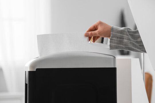 Data privacy and document security, person shredding confidential paper documents to prevent identity theft and protect sensitive corporate information