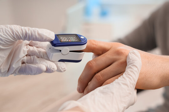 Pulse oximetry and health monitoring, doctor checking blood oxygen saturation levels of a patient with a digital finger sensor in a medical clinic