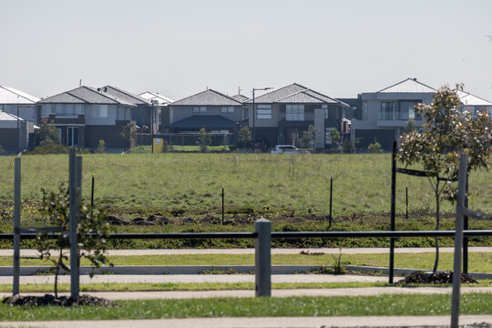 Modern two-storey residential houses in a new housing estate viewed across an open grassy undeveloped land in Truganina. Urban fringe living in an outer suburb of Melbourne, Victoria, Australia.