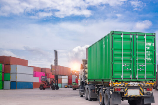 Cargo container truck transporting green shipping container in logistics yard. Global supply chain transport. Human-created, not AI.