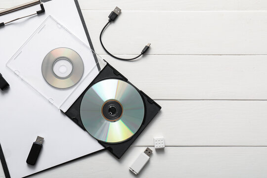 Data storage and digital archiving, compact discs and usb flash drives on a white wooden desk for information technology and computer backup solutions