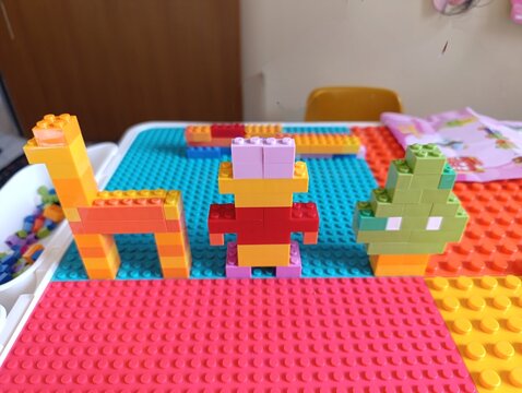 Colorful plastic toy building blocks assembled into animal and plant shapes on a play mat