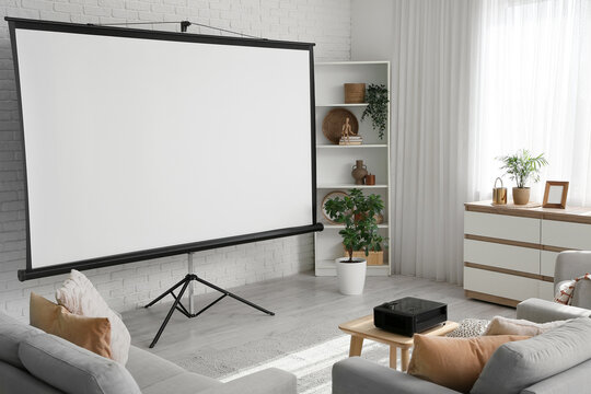 Interior of living room with sofa, shelving unit, commode and projector screen near white brick wall