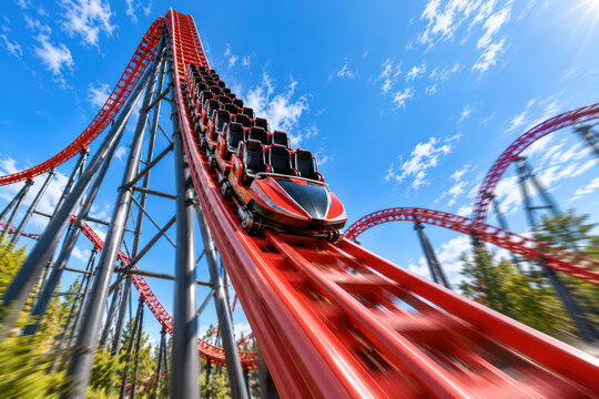Empty roller coaster train plunging down steep red track at high speed
