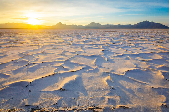Golden sunrise illuminating textured crust at Bonneville Salt Flats Utah