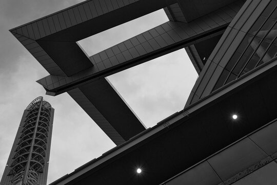 未来都市を思わせる幾何学的な構造物とタワーを見上げるモノクロ建築スナップ