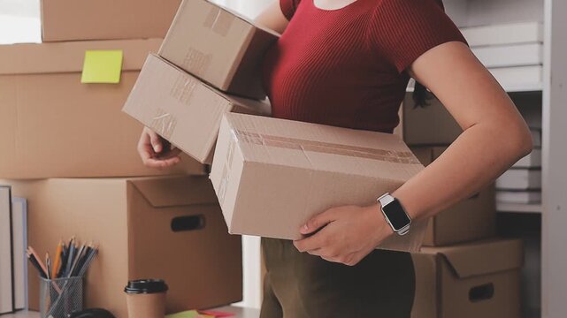 Startup SME small business entrepreneur of freelance Asian woman wearing apron using laptop and box to receive and review orders online to prepare to pack sell to customers, online sme business ideas.