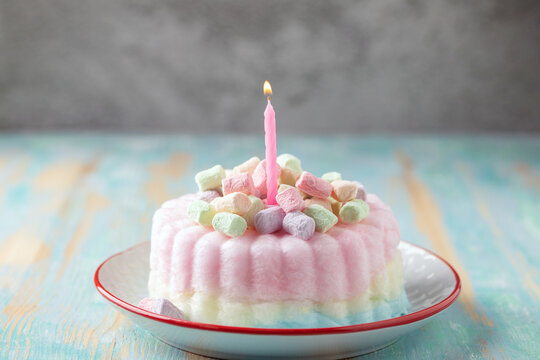 Flaky coloured candyfloss birthday cake in a plate on the table. Trendy sweet dessert