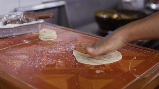 Chef Flattening and Shaping Roti Dough in Commercial Kitchen