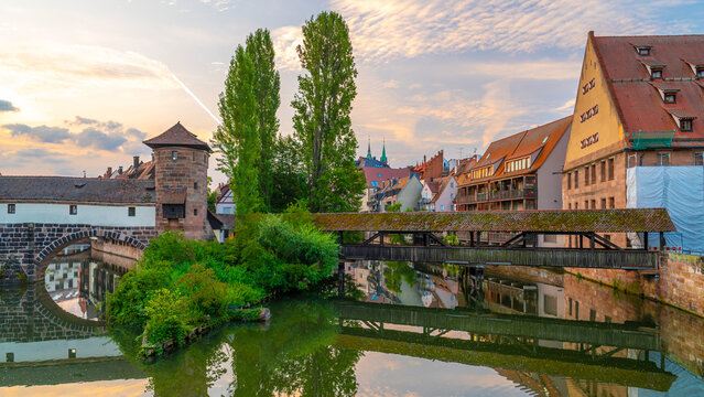 Stunning sunset view of the historic Weinstadel, Henkersteg wooden bridge  reflecting in the calm waters of the Pegnitz River in Nuremberg