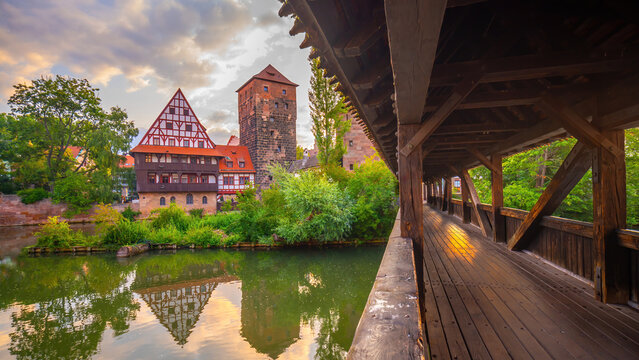 Stunning sunset view of the historic Weinstadel, Henkersteg wooden bridge  reflecting in the calm waters of the Pegnitz River in Nuremberg