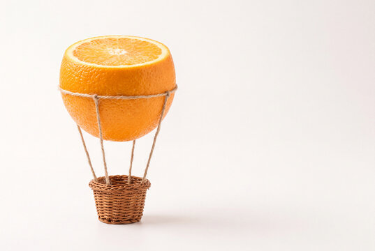 surreal orange fruit hot air balloon on minimal background