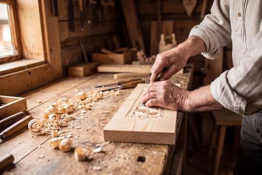 traditional woodcarver carving decorative pattern by hand in rustic workshop