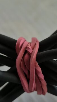 the texture of a red rubber band binding a bundle of black electronic cables