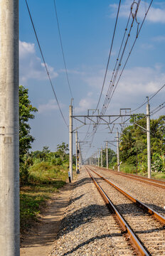Double track railway with overhead electric catenary poles extending into the distance