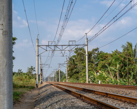 Double track railway with overhead electric catenary poles extending into the distance
