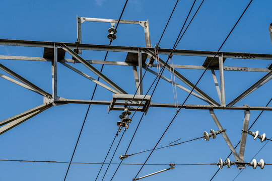 Low angle close-up of overhead railway electrification catenary wire system and steel structure